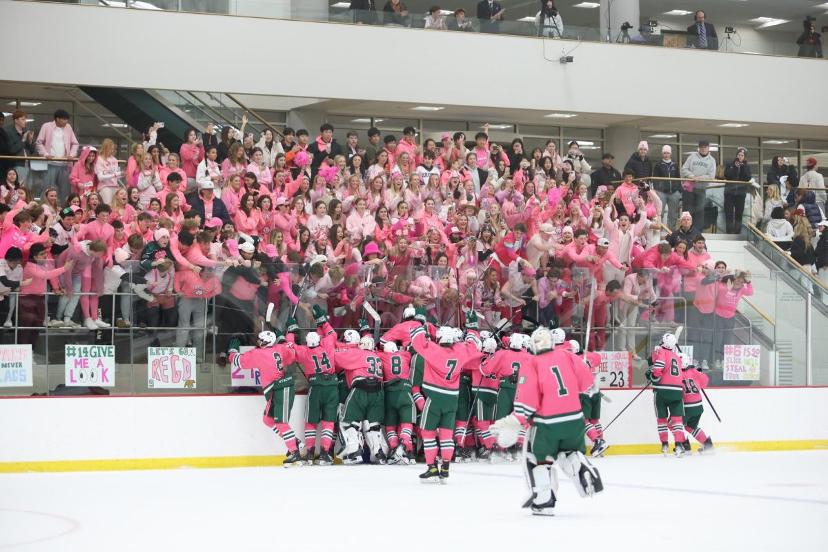 Boys Varsity Hockey celebrates in front of the pinked out home crowd